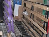 Dans un entrepôt, des cartons et des palettes sont empilés sur un tapis roulant