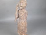 statue représentant une personne portant un chapeau orné d'une plume, posée sur un socle en bois