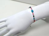 une main de mannequin blanche ornée d'un bracelet coloré