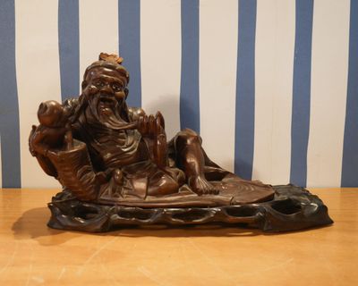 une statue représentant un homme assis dans un bateau avec un chien