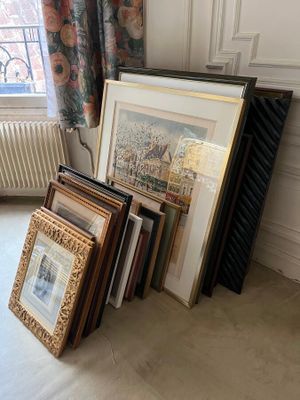 a lot of framed art on the floor in this room