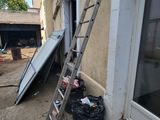 a ladder leaning against a building next to a trash can