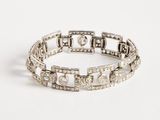 a close up of a diamond bracelet on a white surface