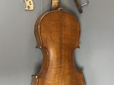 an antique violin with a wooden case and a bow on a gray background