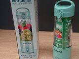 un mixeur posé sur une table à côté d'une corbeille de fruits
