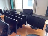 many computer monitors sitting on a desk in a room