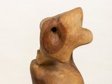 wooden sculpture of a bear sitting on top of a white pedestal