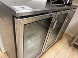 a stainless steel counter with a glass door and a coffee maker