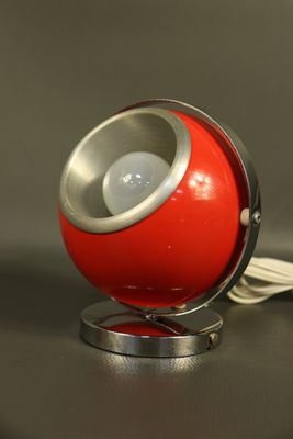 une lampe rouge posée sur un pied en métal