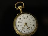an old pocket watch sitting on top of a black surface