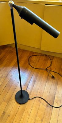 une lampe noire posée sur un plancher en bois