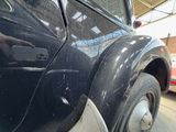 a close up of a black car with a red fire truck in the background