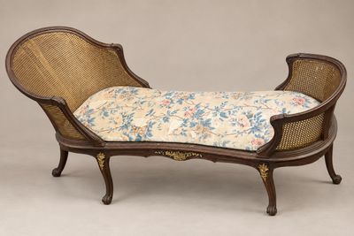 une chaise longue de style ancien avec un coussin rembourré à motifs floraux