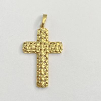un gros plan d'un pendentif en forme de croix dorée sur une surface blanche