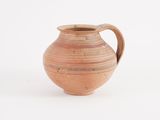 a brown vase with a handle on a white surface