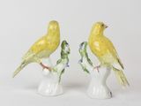 pair of yellow birds sitting on top of a white vase