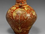 an image of a red and gold vase on a gray background