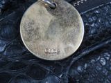 a close up of a silver dog tag on a black purse