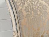 a close up of a chair with a gold and silver pattern