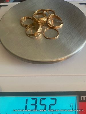 une balance sur laquelle sont posés plusieurs anneaux en or