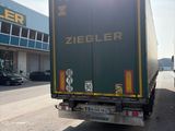 un camion qui roule dans la rue devant un immeuble