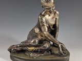 statue en bronze représentant une femme agenouillée sur un rocher, les mains posées sur le sol