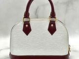 a white and maroon handbag with two handles on a marble surface