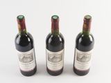three bottles of wine sitting next to each other on a white surface