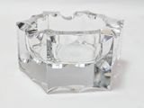 un bougeoir en verre transparent posé sur une surface blanche