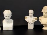 trois busturines blanches de tailles et de formes différentes posées sur une surface noire