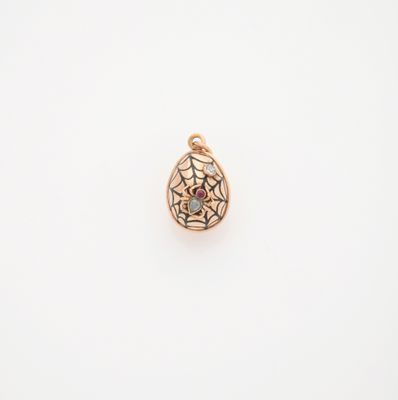 un pendentif en or orné d'une toile d'araignée et d'une pierre rouge