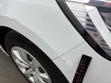 the front end of a white car with a sticker on it ' s bumper