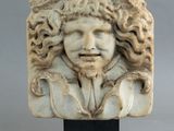 tête sculptée d'un homme aux cheveux bouclés, posée sur un socle noir