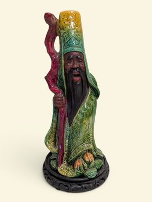 figurine représentant un homme tenant un bâton et un bâton à la main