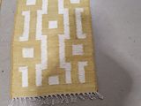 two pieces of yellow and white rugs on a white floor