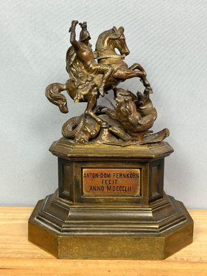 statue en bronze représentant un cheval et son cavalier, posée sur un socle en bois