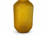 a yellow glass vase that is sitting on a white surface