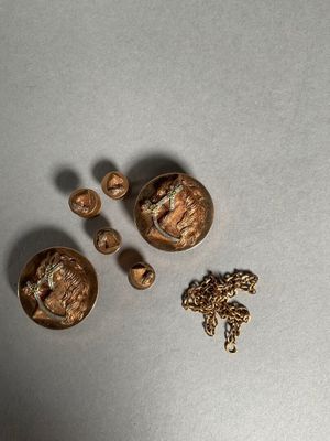 three gold buttons and a gold chain on a table