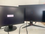 two monitors sitting on a table next to each other