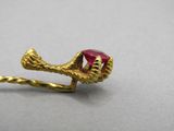 a close up of a gold ring with a red stone on it