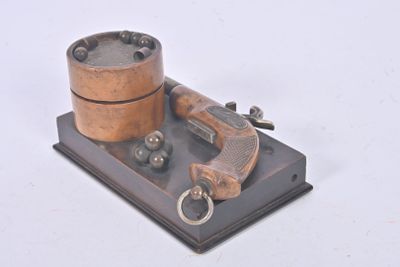 a small metal object with a gun on a stand
