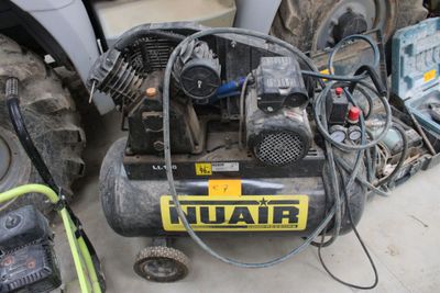 un petit compresseur d'air posé par terre à côté d'un tracteur