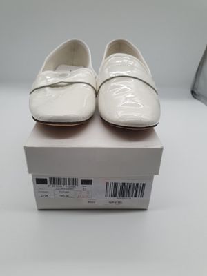 une paire de chaussures blanches posée sur une boîte, elle-même posée sur une table