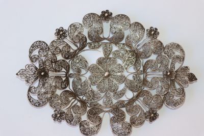 une image représentant une broche en argent posée sur une surface blanche