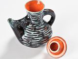 a black and orange vase and a small orange vase on a white surface
