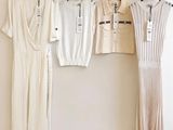 trois robes blanches accrochées à un mur, à côté d'un cintre noir