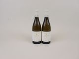 deux bouteilles de vin posées l'une à côté de l'autre sur une surface blanche