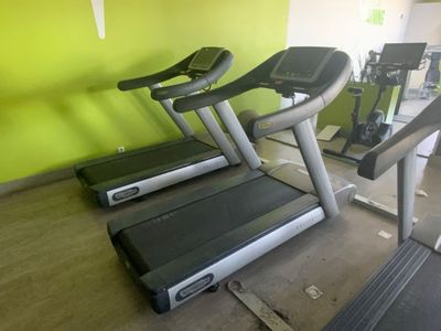 deux appareils de cardio dans une salle de sport aux murs verts