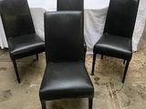 trois fauteuils en cuir noir placés devant une table blanche
