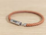 leather bracelet with a metal clasp on a wooden surface